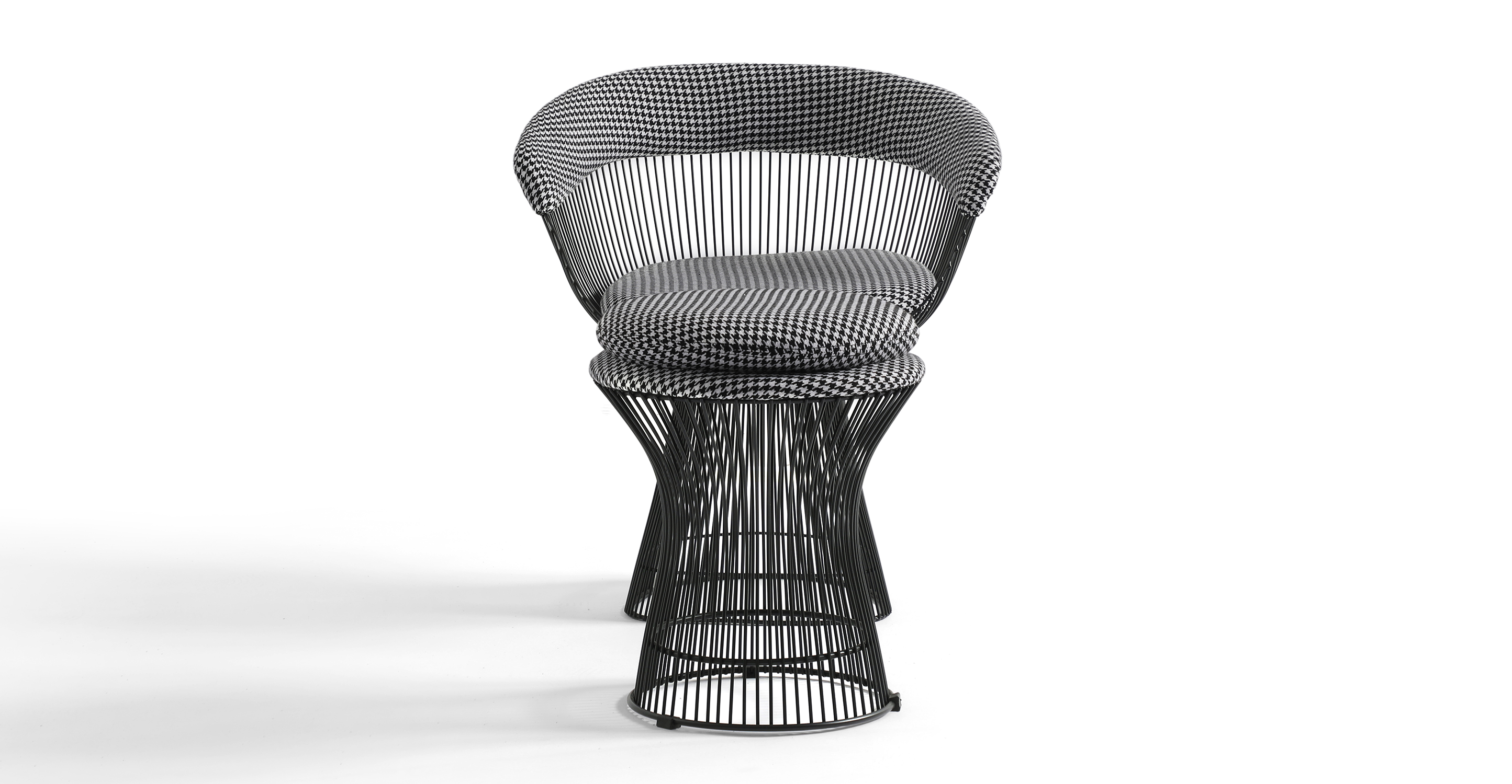 The Platner dining chairs have a wide base that tapers up and meets a bucket seat also made of black stainless steel rods. The arms and black are cushioned with upholstery and the seat has a removable cushion. 