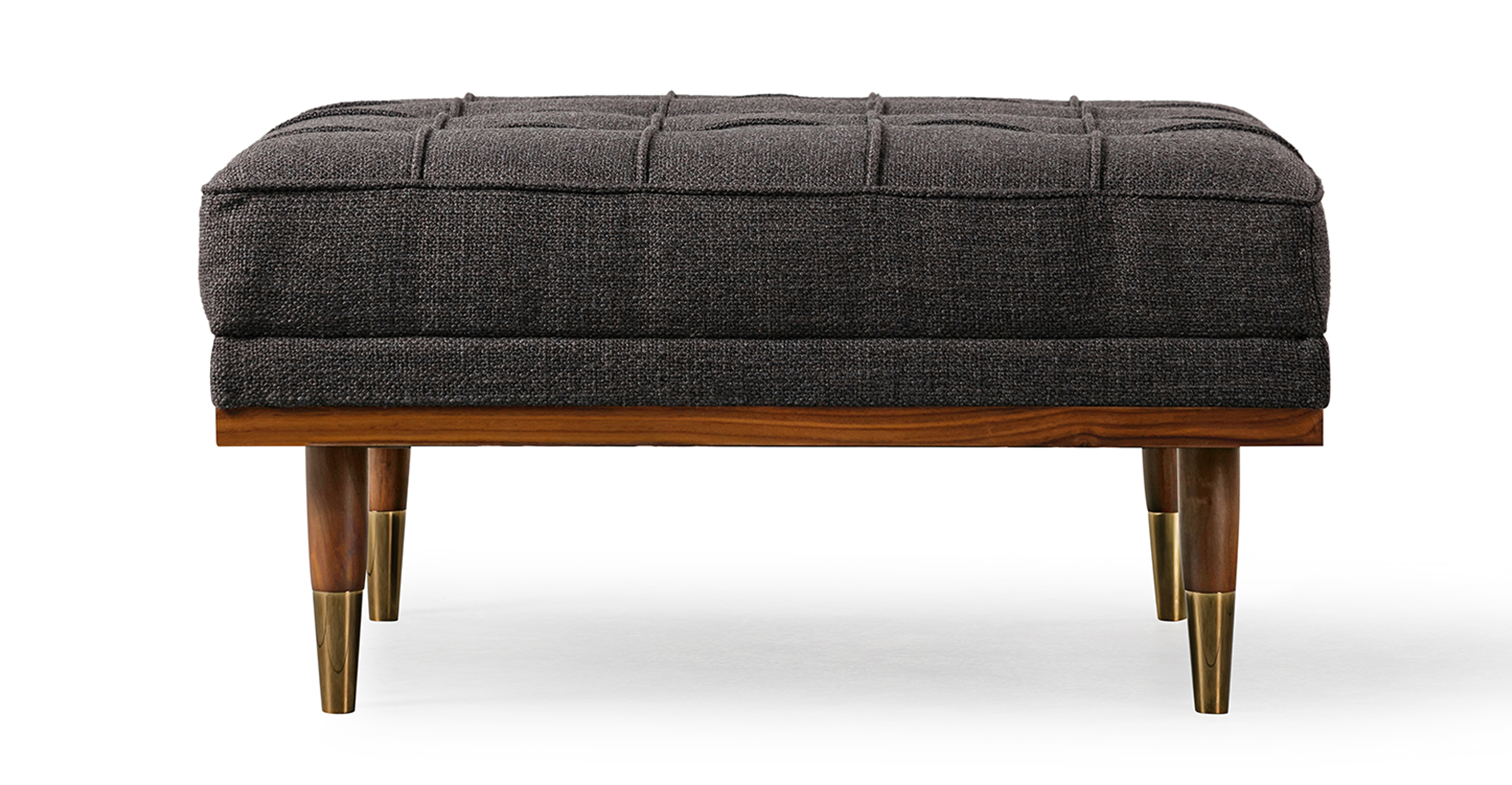 Image shows side picture of Mid-Century Modern Woodrow Box Ottoman in Elyx Belgian Woven Dior Grey Fabric. Frame and legs are walnut wood. Legs are brass tipped walnut wood. The cushion is button tufted. 