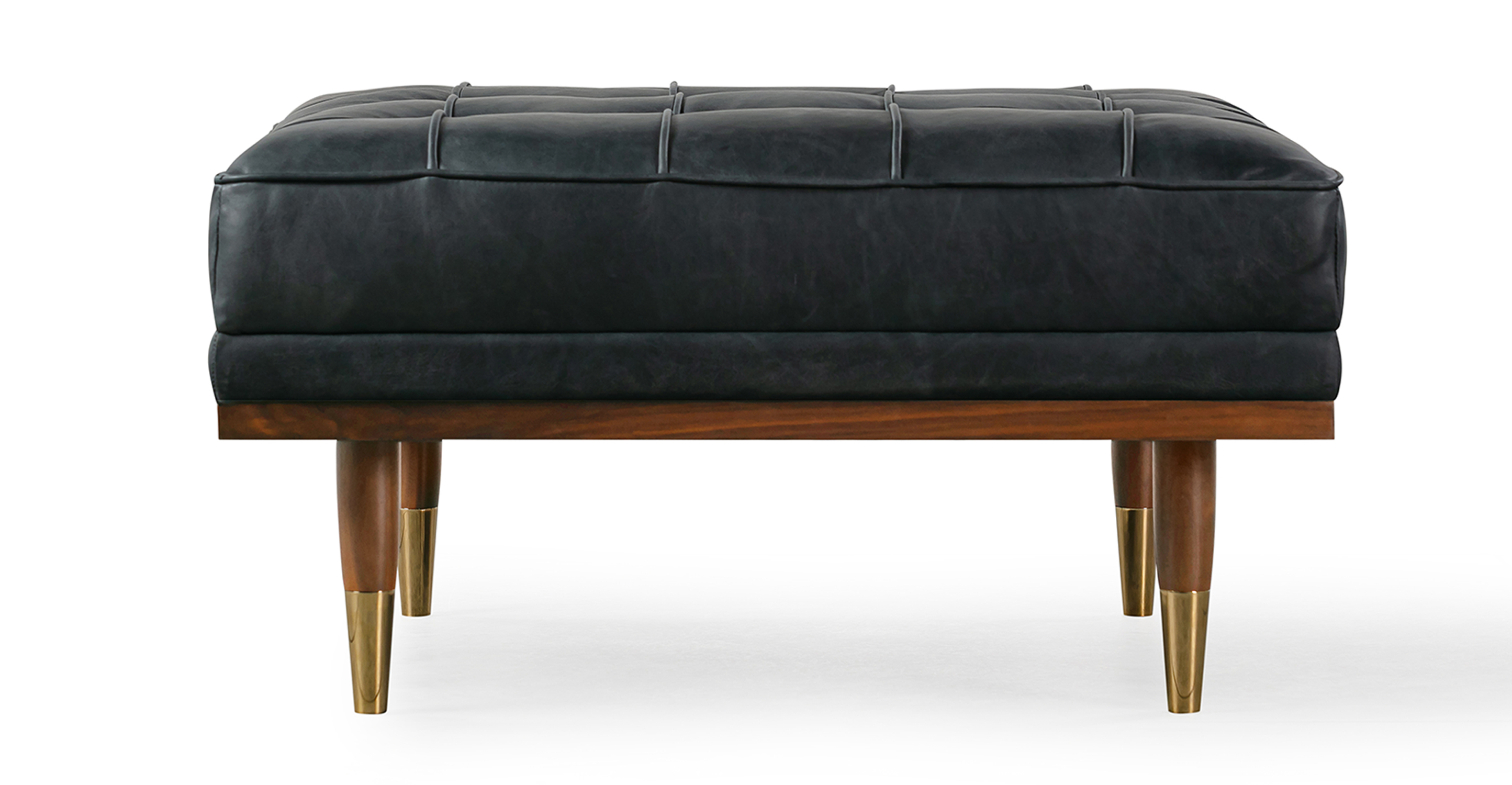 Image shows side picture of Mid-Century Modern Woodrow Box Ottoman in Milano Black Leather. Frame and legs are walnut wood. Legs are brass tipped walnut wood. The cushion is button tufted. 